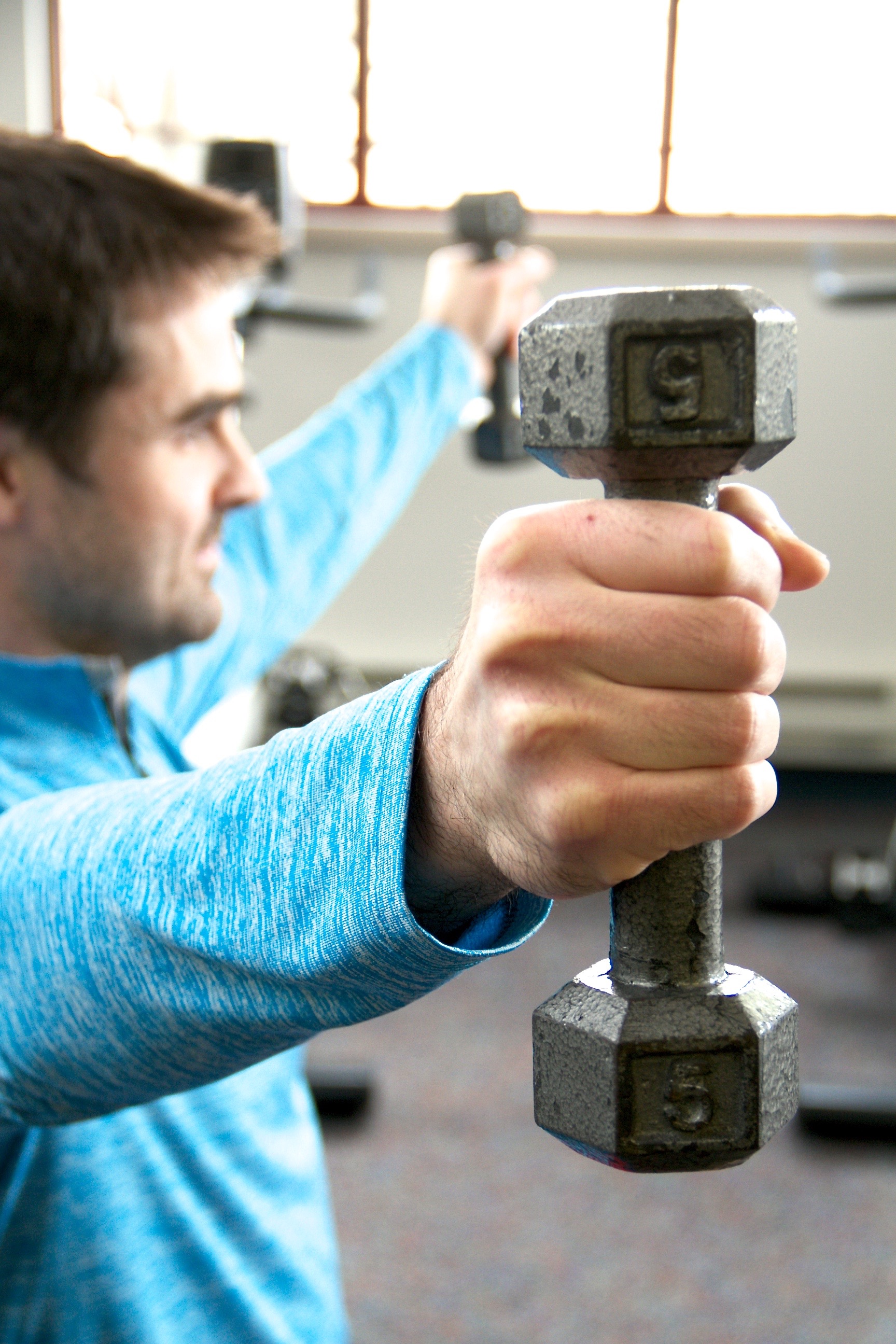 Man holding free weights at arms length